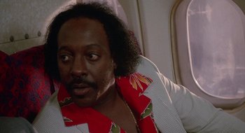 Movie still from “Commando” (1985), directed by Mark L. Lester – A person sitting on a plane; Close Up shot, Low angle