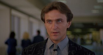 Movie still from “Commando” (1985), directed by Mark L. Lester – A person wearing a suit and tie; Close Up shot, Low angle
