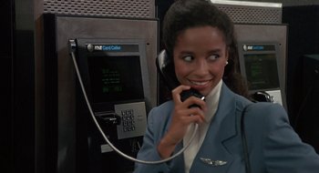 Movie still from “Commando” (1985), directed by Mark L. Lester – A woman is talking on a phone while wearing a suit; Close Up shot, Low angle