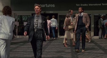 Movie still from “Commando” (1985), directed by Mark L. Lester – A group of people walking down a sidewalk; Medium shot, Low angle
