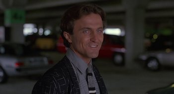 Movie still from “Commando” (1985), directed by Mark L. Lester – A person wearing a suit and tie; Close Up shot, Low angle