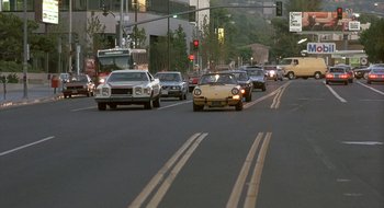 Movie still from “Commando” (1985), directed by Mark L. Lester – Cars are driving down a busy city street at night; Extreme Wide shot, High angle