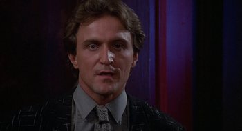 Movie still from “Commando” (1985), directed by Mark L. Lester – A person wearing a suit and tie; Close Up shot, Low angle