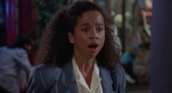 Movie still from “Commando” (1985), directed by Mark L. Lester – A young woman with curly black hair wearing a white shirt and a blue jacket; Close Up shot, High angle