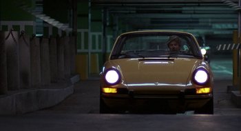 Movie still from “Commando” (1985), directed by Mark L. Lester – A man sitting in the driver's seat of a yellow car; Wide shot, High angle