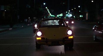 Movie still from “Commando” (1985), directed by Mark L. Lester – A car driving down a street at night; Wide shot, Low angle