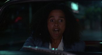Movie still from “Commando” (1985), directed by Mark L. Lester – A woman with a surprised look on her face in a car; Close Up shot, Low angle