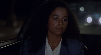 Movie still from “Commando” (1985), directed by Mark L. Lester – A woman with long black hair is looking at the camera; Close Up shot, Over the shoulder angle