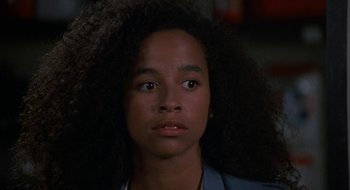 Movie still from “Commando” (1985), directed by Mark L. Lester – A young woman with long black hair looking at the camera; Close Up shot, Over the shoulder angle