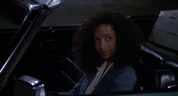 Movie still from “Commando” (1985), directed by Mark L. Lester – A woman sitting in the driver's seat of a car; Close Up shot, High angle