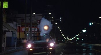Movie still from “Commando” (1985), directed by Mark L. Lester – A car that is driving down the street at night; Extreme Wide shot, Low angle
