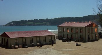 Movie still from “Commando” (1985), directed by Mark L. Lester – A couple of buildings that are next to each other; Extreme Wide shot, High angle