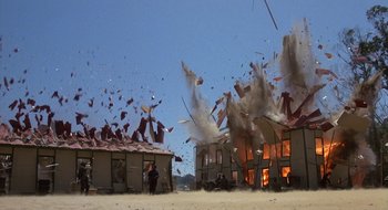 Movie still from “Commando” (1985), directed by Mark L. Lester – A building that has been destroyed by a fire; Extreme Wide shot, Low angle