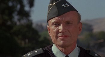 Movie still from “Commando” (1985), directed by Mark L. Lester – An older man wearing a uniform and a hat; Close Up shot, Low angle