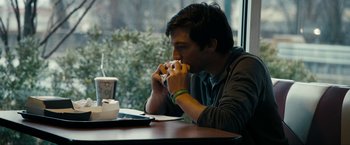 Movie still from “Compliance” (2012), directed by Craig Zobel – A man sitting at a table eating a sandwich; Medium shot, Over the shoulder angle