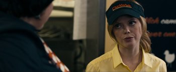 Movie still from “Compliance” (2012), directed by Craig Zobel – A woman in a yellow shirt wearing a hat; Close Up shot, Over the shoulder angle