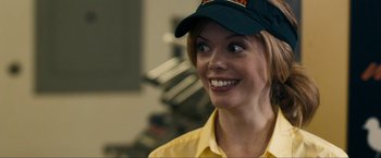 Movie still from “Compliance” (2012), directed by Craig Zobel – A woman wearing a baseball cap and a yellow shirt; Close Up shot, Over the shoulder angle