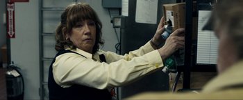 Movie still from “Compliance” (2012), directed by Craig Zobel – A woman in a yellow shirt is holding a box; Close Up shot, Over the shoulder angle