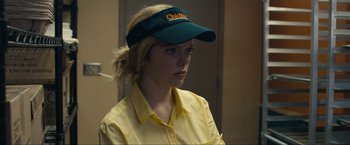 Movie still from “Compliance” (2012), directed by Craig Zobel – A woman in a yellow shirt wearing a green visor; Close Up shot, Over the shoulder angle