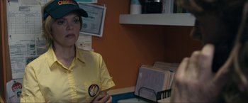 Movie still from “Compliance” (2012), directed by Craig Zobel – A woman in a yellow shirt is holding a pen; Medium shot, Over the shoulder angle