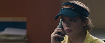 Movie still from “Compliance” (2012), directed by Craig Zobel – A woman wearing a hat talking on a cell phone; Close Up shot, Over the shoulder angle