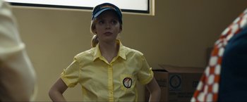 Movie still from “Compliance” (2012), directed by Craig Zobel – A woman in a yellow shirt and a blue hat; Medium shot, Over the shoulder angle