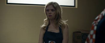 Movie still from “Compliance” (2012), directed by Craig Zobel – A woman in an apron is standing in front of a projector screen; Close Up shot, Low angle