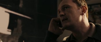 Movie still from “Compliance” (2012), directed by Craig Zobel – A man talking on a cell phone in a dimly - lit room; Close Up shot, Low angle
