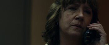 Movie still from “Compliance” (2012), directed by Craig Zobel – A woman's face in a dark room; Close Up shot, Over the shoulder angle