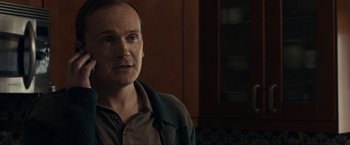 Movie still from “Compliance” (2012), directed by Craig Zobel – A man standing in front of a wooden cabinet; Close Up shot, Over the shoulder angle