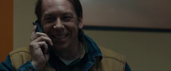 Movie still from “Compliance” (2012), directed by Craig Zobel – A man smiling for the camera while wearing a jacket; Close Up shot, Low angle