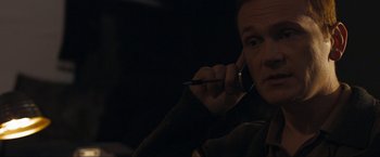 Movie still from “Compliance” (2012), directed by Craig Zobel – A man talking on a cell phone while holding a pen; Close Up shot, Over the shoulder angle