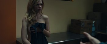 Movie still from “Compliance” (2012), directed by Craig Zobel – A woman standing in front of a mirror in front of a wall; Medium shot, Over the shoulder angle