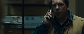 Movie still from “Compliance” (2012), directed by Craig Zobel – A man holding a cell phone up to his ear; Close Up shot, Over the shoulder angle
