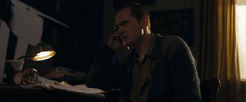 Movie still from “Compliance” (2012), directed by Craig Zobel – A man sitting at a table talking on a phone; Medium shot, Over the shoulder angle