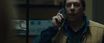 Movie still from “Compliance” (2012), directed by Craig Zobel – A man holding a cell phone up to his ear; Close Up shot, Over the shoulder angle