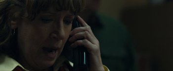 Movie still from “Compliance” (2012), directed by Craig Zobel – A person talking on a cell phone while sitting down; Close Up shot, Over the shoulder angle
