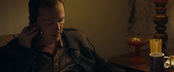 Movie still from “Compliance” (2012), directed by Craig Zobel – A man sitting on a couch in a dark room; Close Up shot, Over the shoulder angle