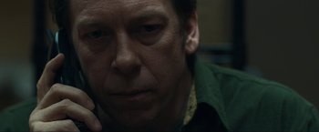 Movie still from “Compliance” (2012), directed by Craig Zobel – A man's face while holding a cell phone to his ear; Close Up shot, Over the shoulder angle