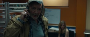 Movie still from “Compliance” (2012), directed by Craig Zobel – An older man talking on a cell phone in a room; Close Up shot, Over the shoulder angle