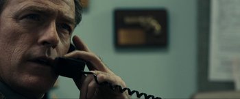 Movie still from “Compliance” (2012), directed by Craig Zobel – A man is talking on a phone in a room; Close Up shot, Over the shoulder angle