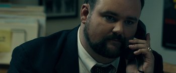 Movie still from “Compliance” (2012), directed by Craig Zobel – A person wearing a suit and tie; Close Up shot, Over the shoulder angle