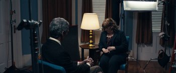 Movie still from “Compliance” (2012), directed by Craig Zobel – A man and a woman sitting in a room with a lamp; Medium shot, Over the shoulder angle