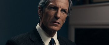 Movie still from “Compliance” (2012), directed by Craig Zobel – An older man wearing a suit and tie; Close Up shot, Over the shoulder angle