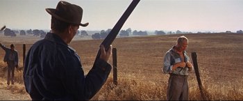 Movie still from “Cool Hand Luke” (1967), directed by Stuart Rosenberg – A man holding a rifle in a field; Wide shot, Over the shoulder angle