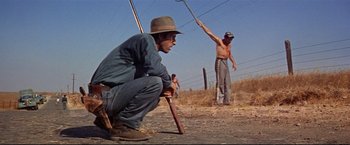 Movie still from “Cool Hand Luke” (1967), directed by Stuart Rosenberg – Two men are standing in a field with a pole; Wide shot, Low angle