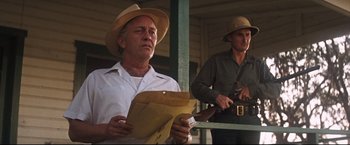 Movie still from “Cool Hand Luke” (1967), directed by Stuart Rosenberg – A man in a straw hat holding papers and standing next to another man in a green shirt; Medium shot, Low angle