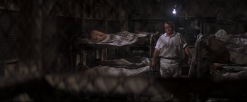 Movie still from “Cool Hand Luke” (1967), directed by Stuart Rosenberg – A man standing next to a group of people sleeping on bunkbeds; Wide shot, High angle