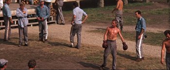 Movie still from “Cool Hand Luke” (1967), directed by Stuart Rosenberg – A group of men standing on top of a dirt field; Wide shot, High angle