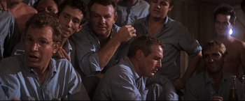 Movie still from “Cool Hand Luke” (1967), directed by Stuart Rosenberg – A group of men sitting next to each other in a room; Medium shot, High angle